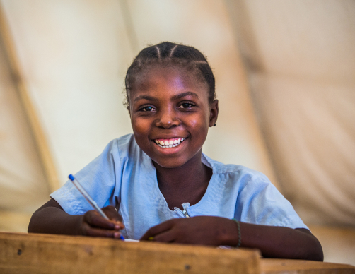 Child writing with a smile